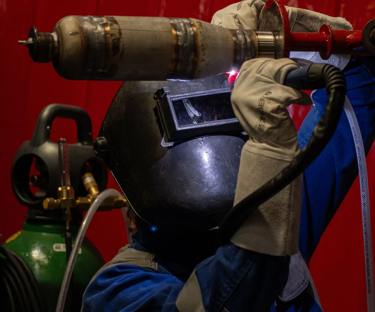 Un finaliste soude au-dessus de sa tête, masque ventilé et bouteille de gaz, finale 2025